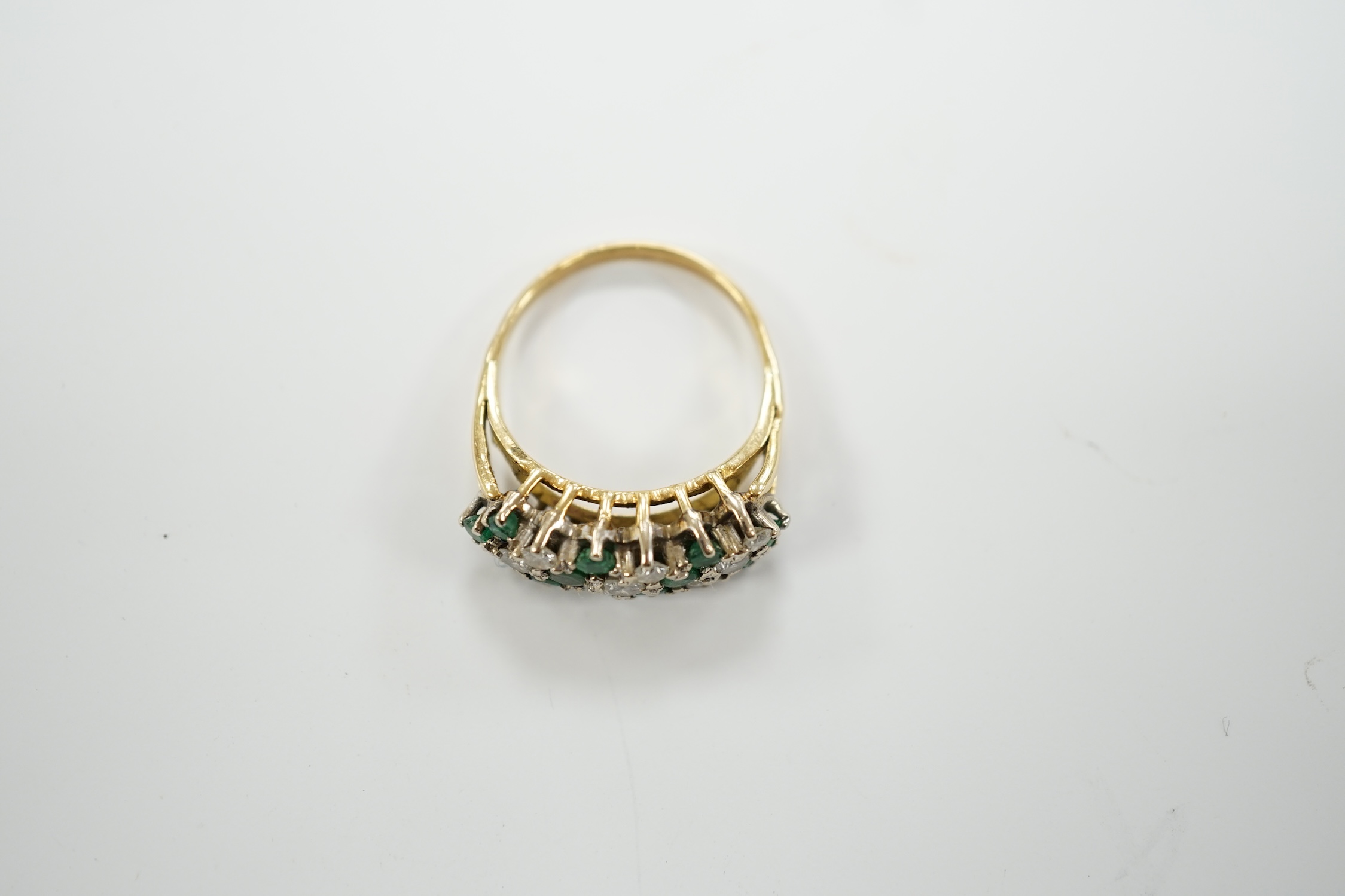 A modern 18ct, emerald and diamond set cluster half hoop ring, size O, gross weight 4.9 grams.